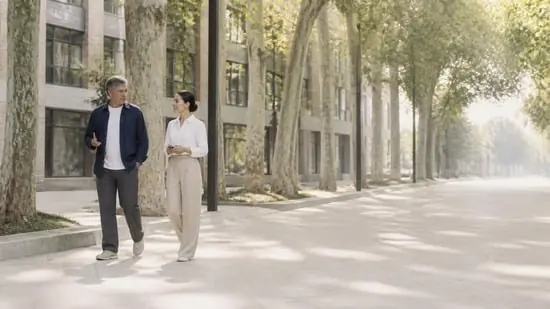 Two founders talking as they walk along a tree-lined boulevard
